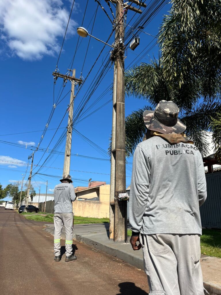 Técnicos em levantamento de campo para cadastro de iluminação pública em Foz do Iguaçu, junto a postes e luminárias.